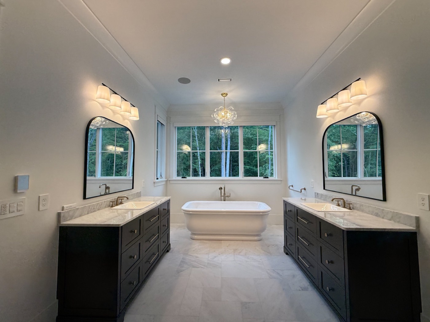 Primary bath with dual vanities, sconces, and chandelier